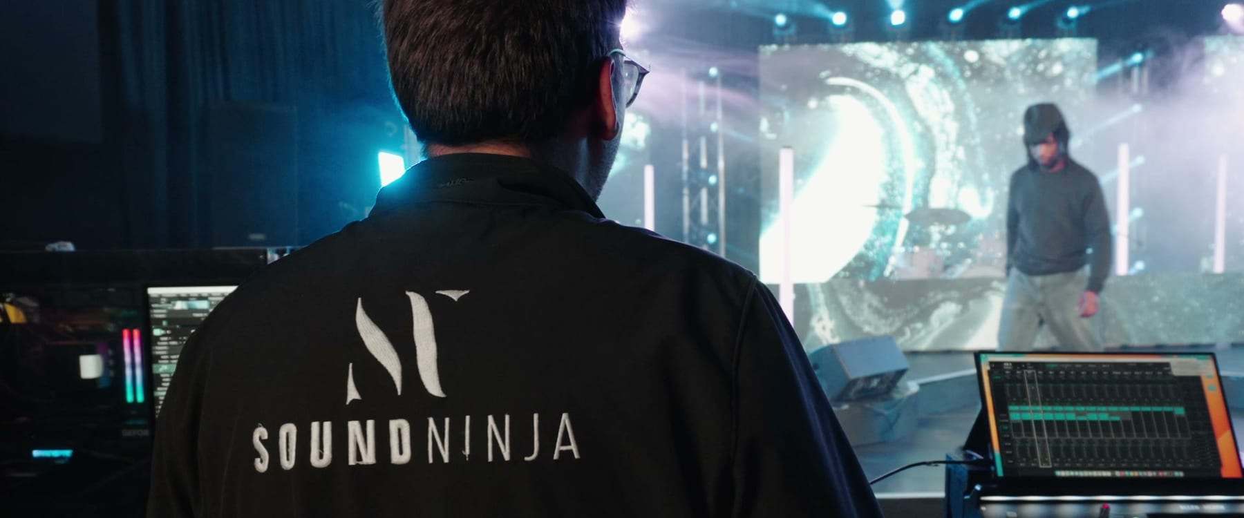A Sound Ninja crew member at the desk facing the stage and the LED screen