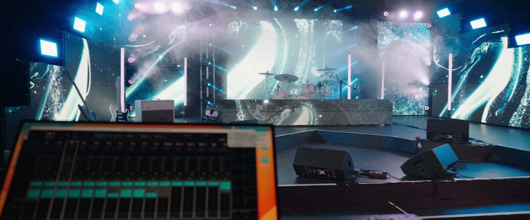 The stage seen from the mixing desk, with LED screens, haze and lights