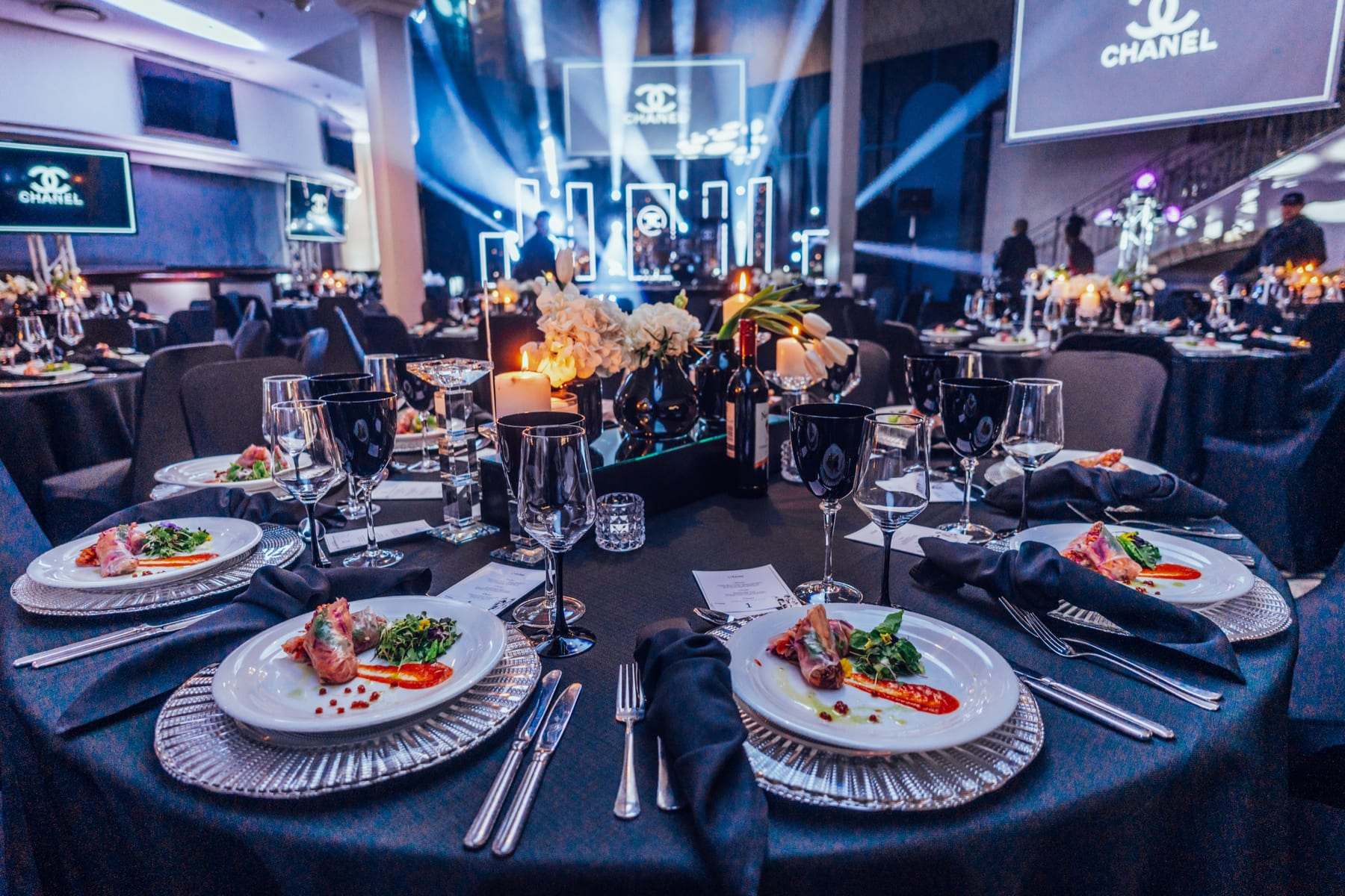 Gala tables under blue light with the Chanel logo on the screen
