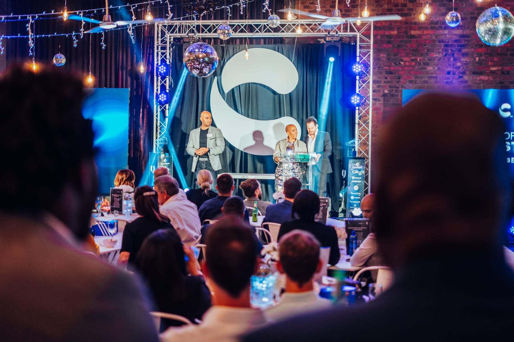 Award winners on stage under the truss frame, seen over the audience