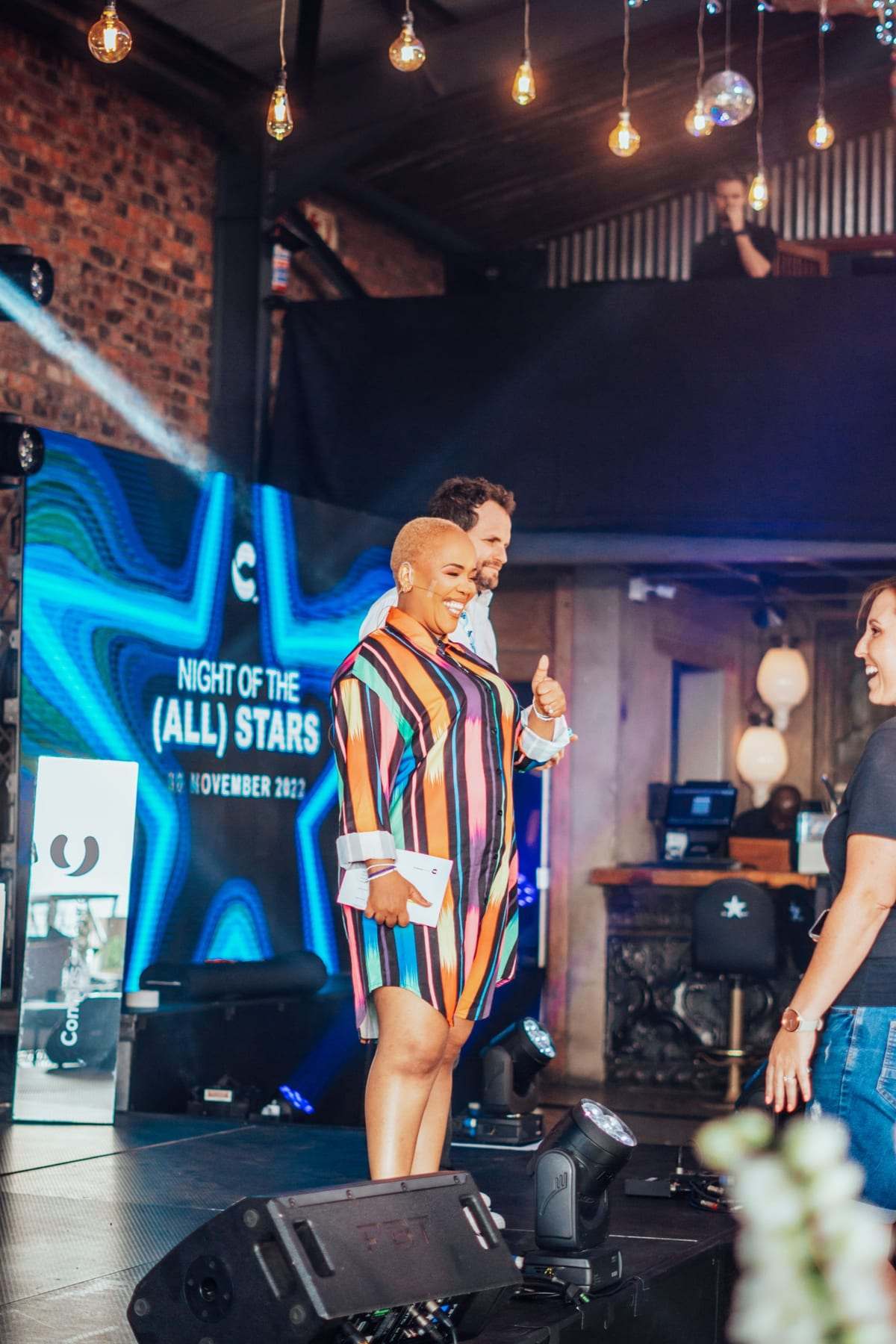 The MC on stage next to the LED screen and a PA speaker