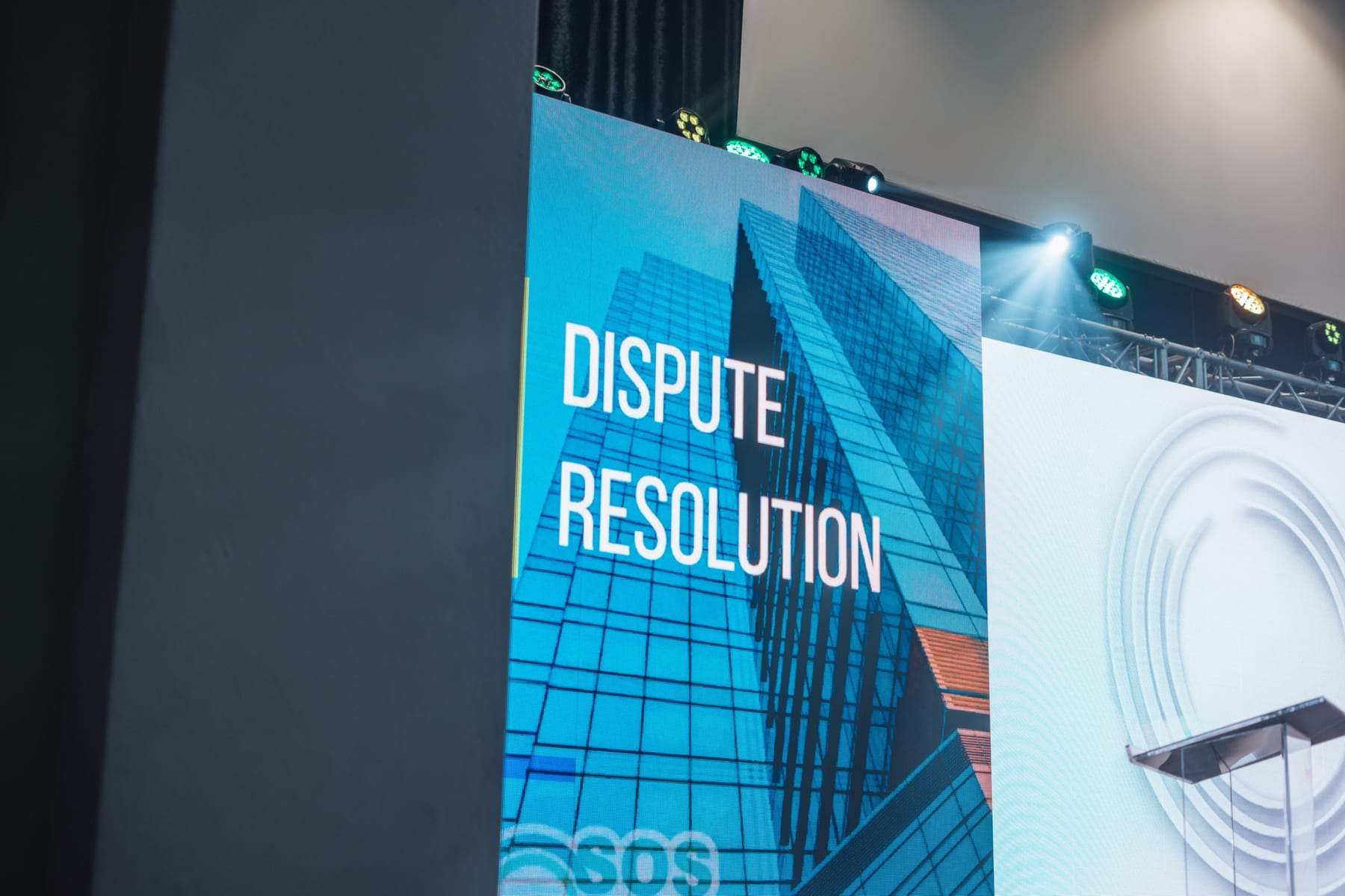 A Dispute Resolution slide on the LED screen next to the stage