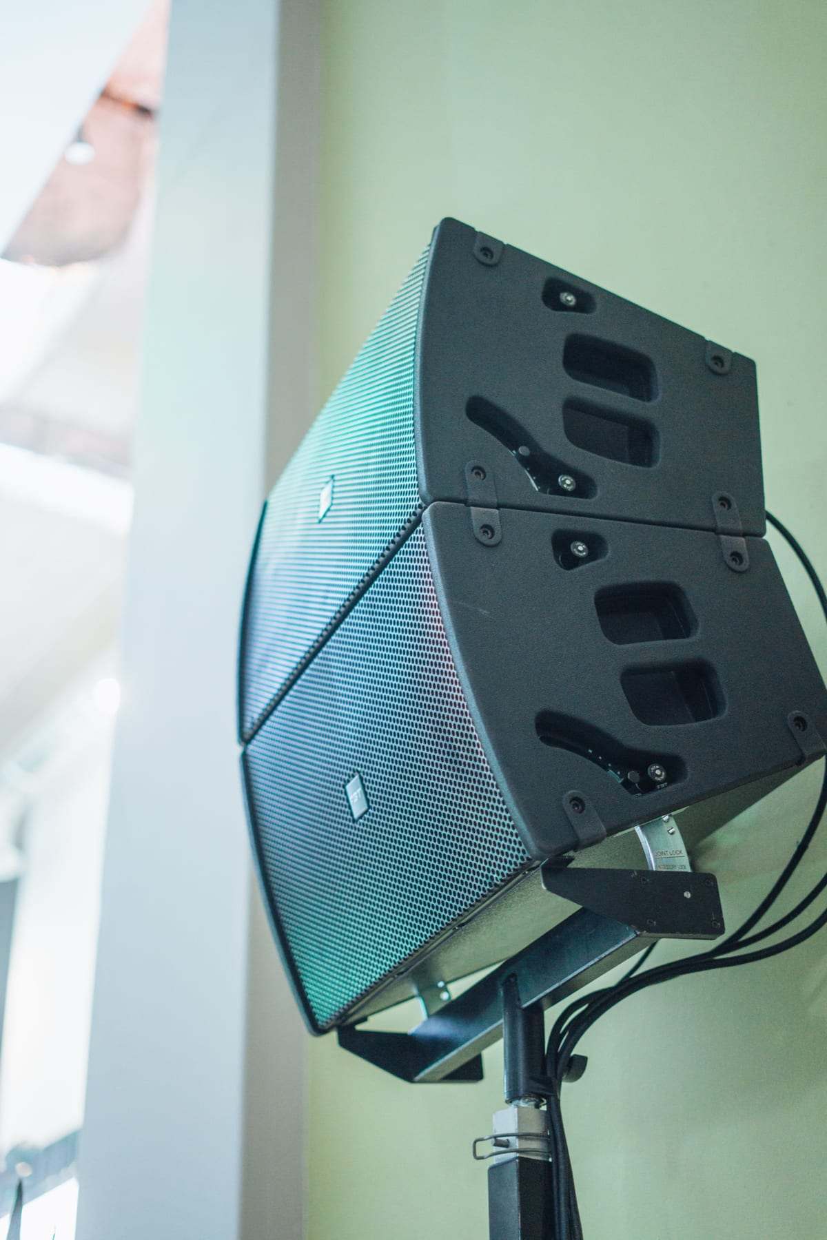 A PA speaker on a stand at the side of the room