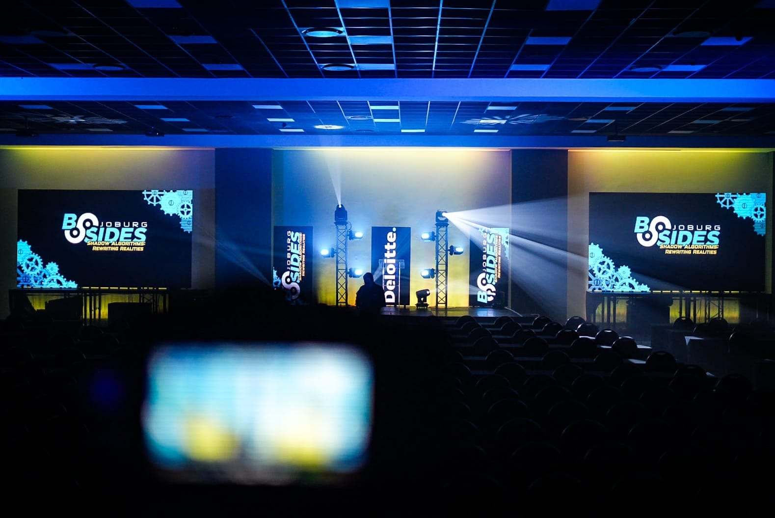 LED screens either side of the stage and truss towers lit in blue and gold