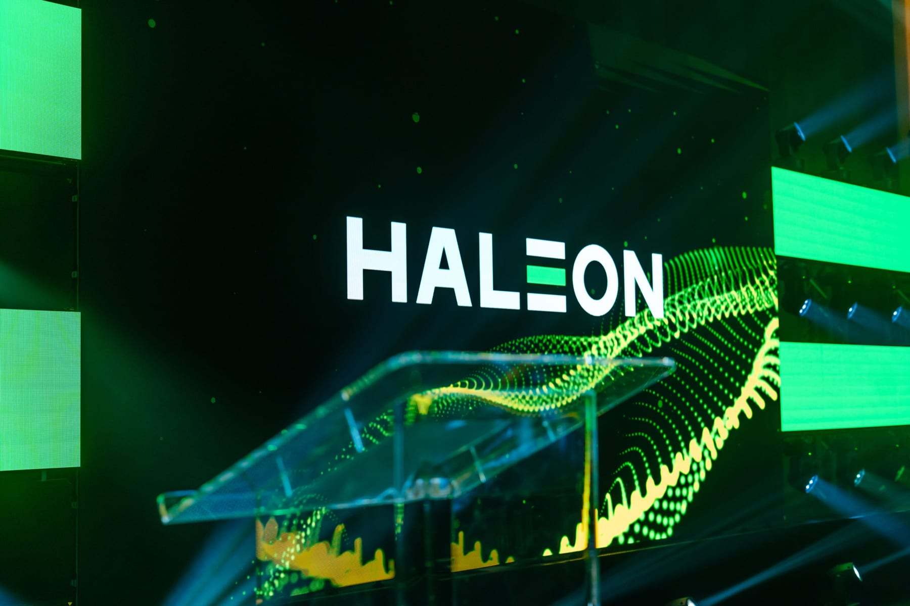 A clear lectern on the Haleon stage in front of the green LED wall