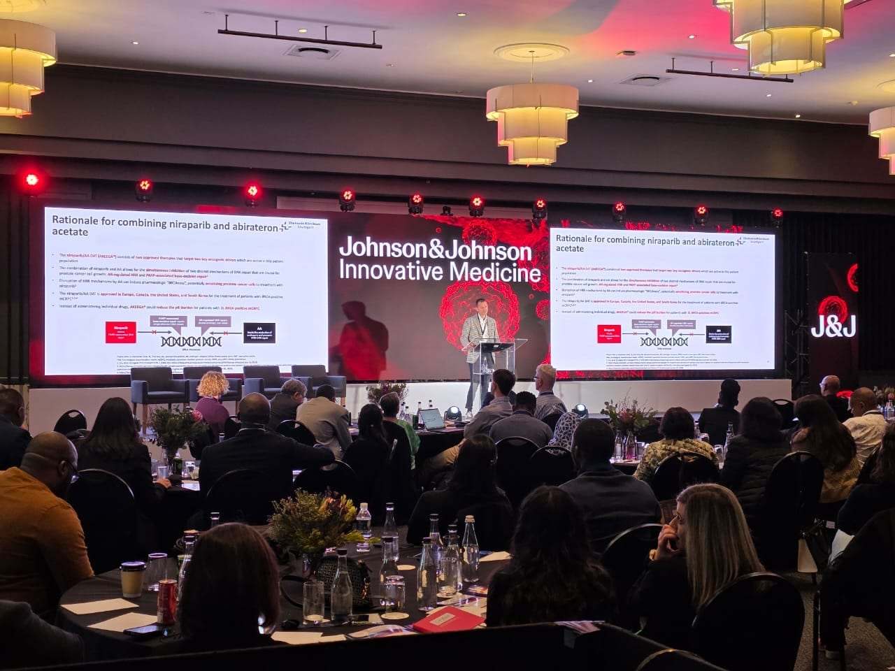 A Johnson & Johnson Innovative Medicine conference with LED screens either side of the stage