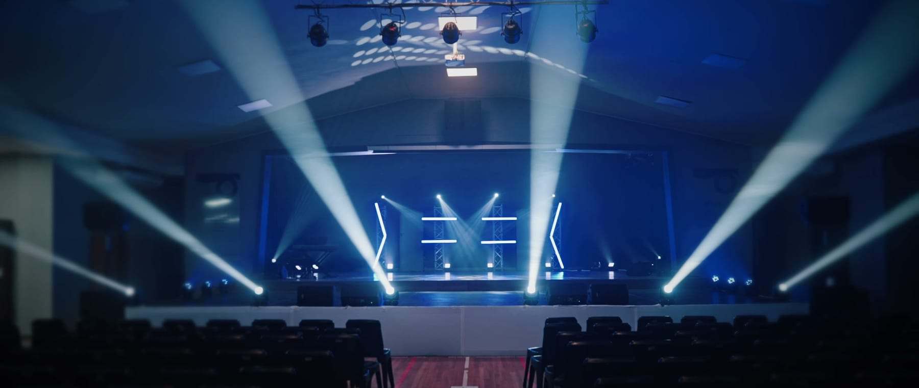 The empty school hall with beams across the stage before the show