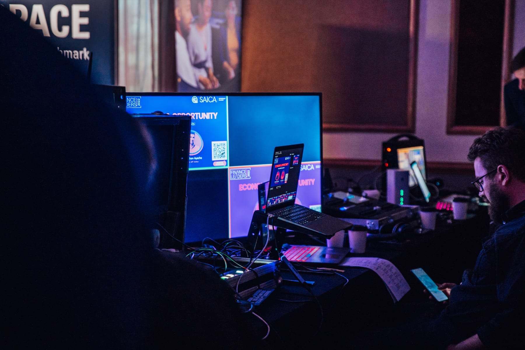 A technician at the control desk with laptops and screens