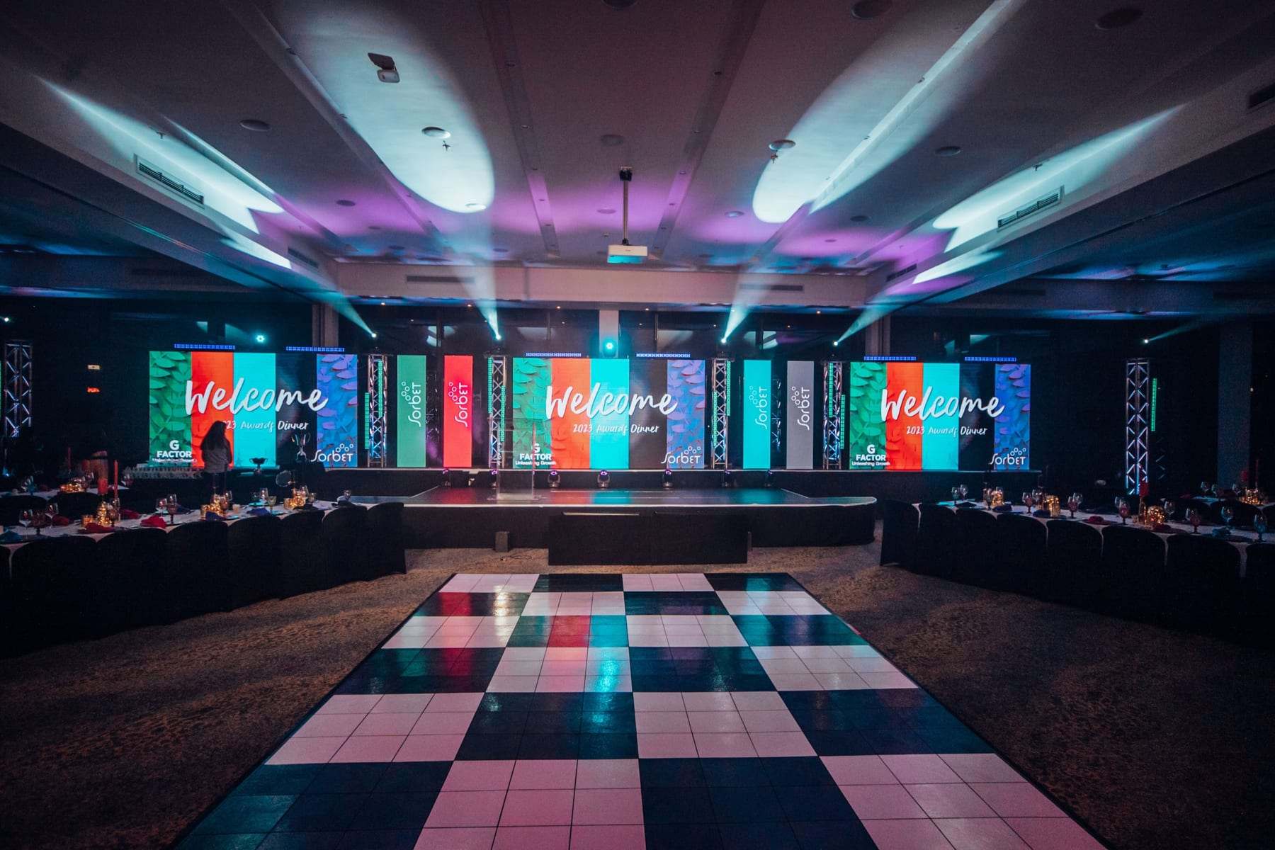 A Welcome message on the LED wall behind a checkerboard dance floor