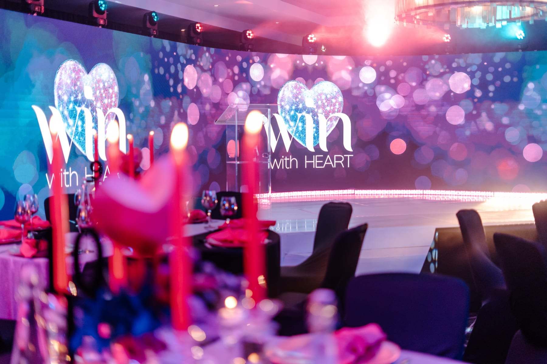 The Win with HEART LED wall behind dinner tables with candles